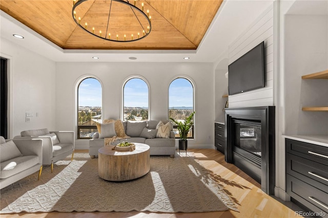 living room with light wood-type flooring, a tray ceiling, and wooden ceiling