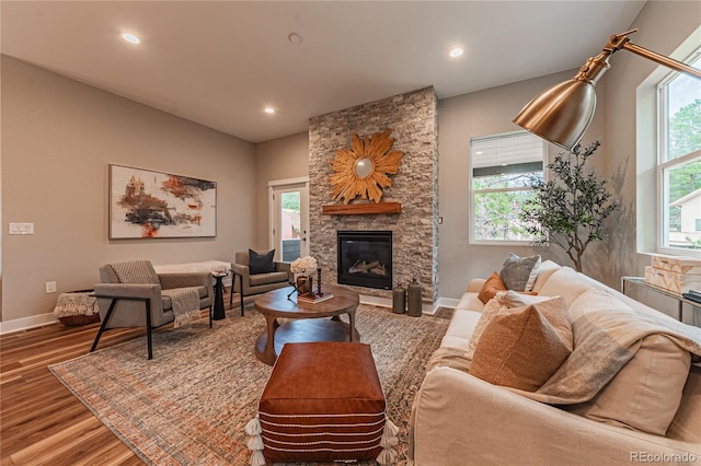 living room with hardwood / wood-style flooring, a stone fireplace, and a wealth of natural light