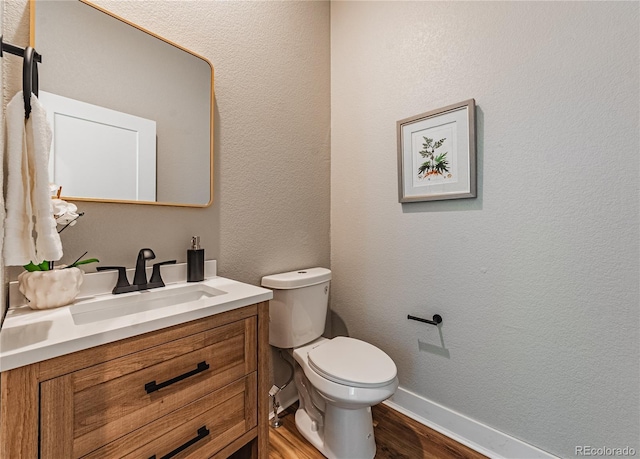 bathroom with vanity, toilet, and hardwood / wood-style floors