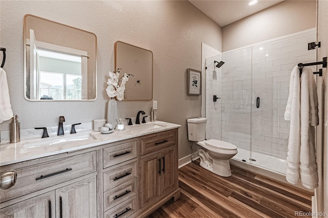 bathroom featuring vanity, hardwood / wood-style flooring, a shower with shower door, and toilet