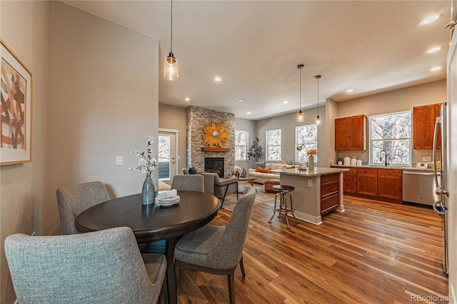 dining area featuring wood-type flooring, a stone fireplace, and sink