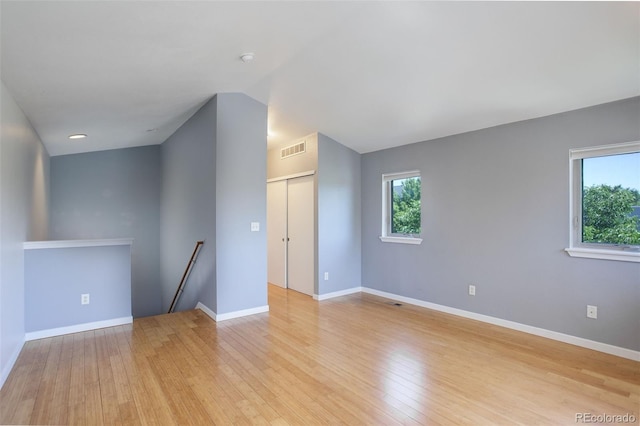 empty room featuring light wood-style floors, visible vents, plenty of natural light, and baseboards