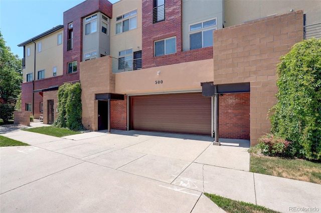 view of front facade with a garage, concrete driveway, brick siding, and stucco siding