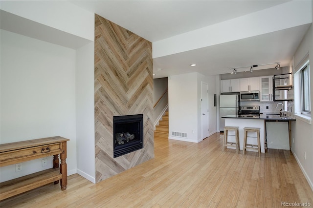 kitchen featuring dark countertops, visible vents, appliances with stainless steel finishes, white cabinetry, and a multi sided fireplace