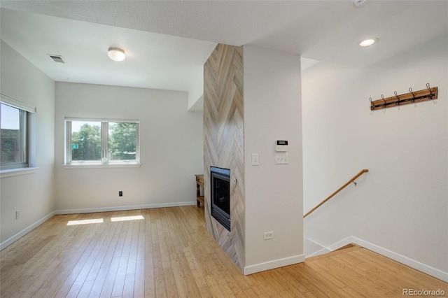 unfurnished living room featuring light wood finished floors, baseboards, a fireplace, and visible vents