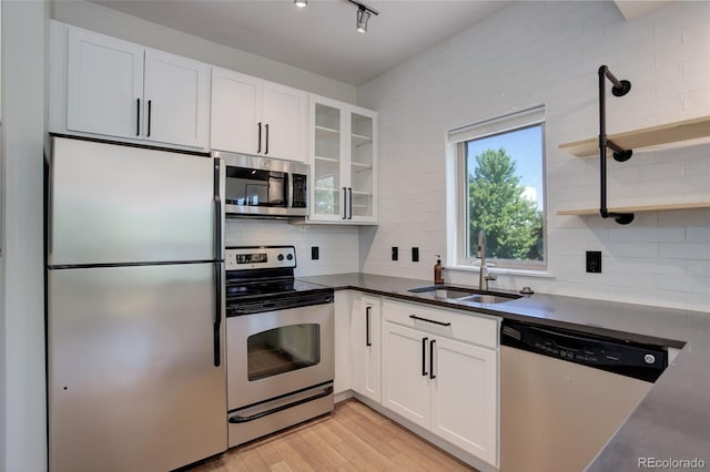 kitchen with appliances with stainless steel finishes, light wood-type flooring, a sink, and white cabinets