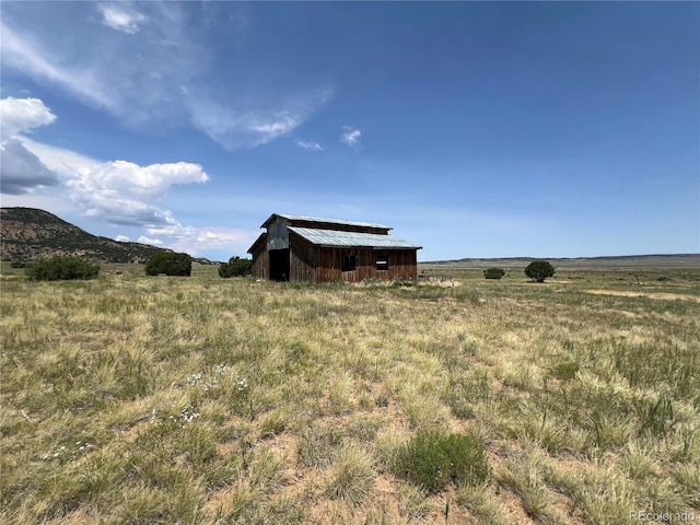 view of yard with a rural view, a pole building, and an outbuilding