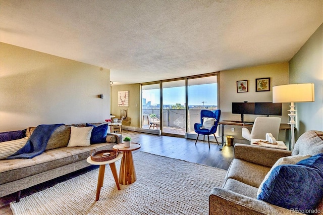 living area with a wall of windows, a textured ceiling, a baseboard heating unit, and wood finished floors