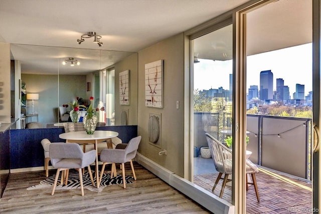 dining space with a city view, floor to ceiling windows, and wood finished floors
