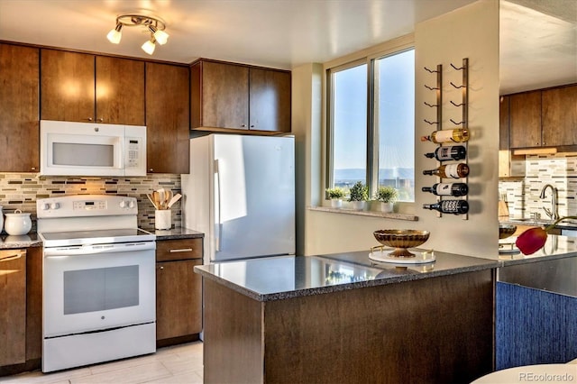 kitchen featuring a sink, backsplash, and white appliances