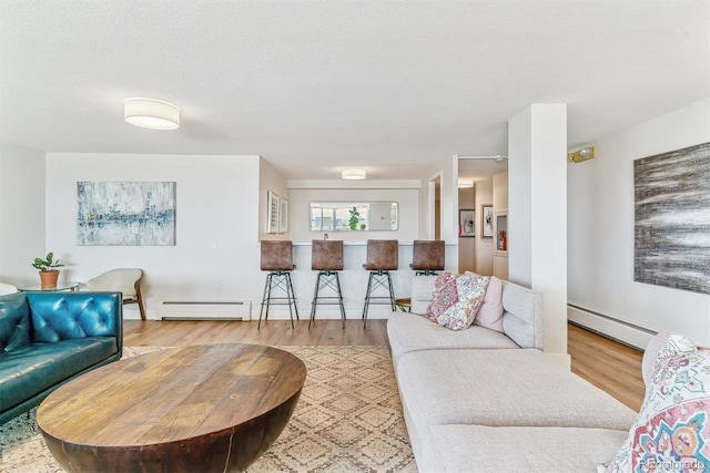 living area featuring a textured ceiling, a baseboard heating unit, and wood finished floors