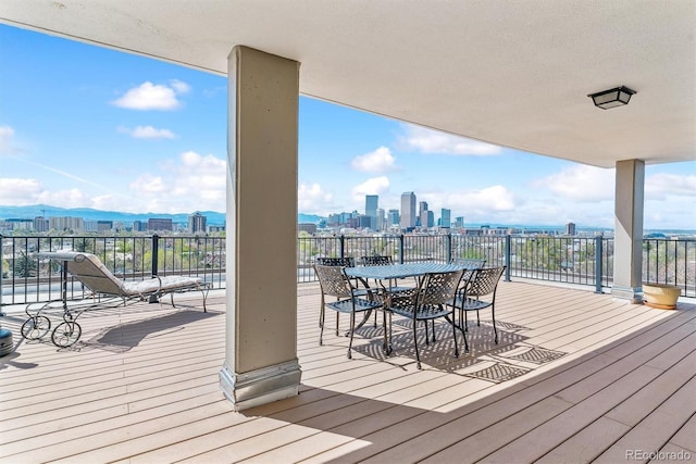 wooden deck featuring outdoor dining area and a city view