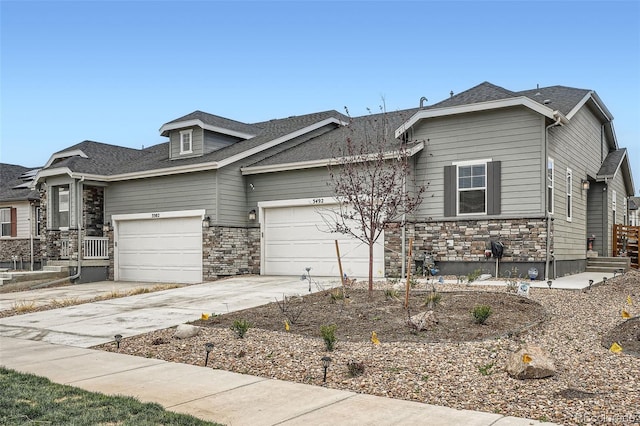 view of front of house featuring stone siding, driveway, and a garage
