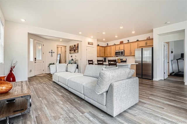 living room with light wood-type flooring, recessed lighting, and baseboards