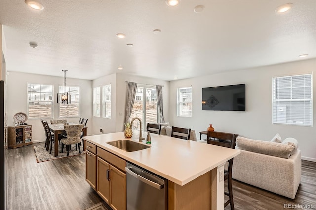 kitchen featuring a sink, dishwasher, open floor plan, dark wood-style floors, and a center island with sink