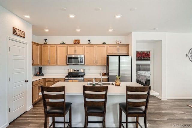 kitchen featuring stainless steel appliances, dark wood-style flooring, light countertops, a kitchen island with sink, and recessed lighting