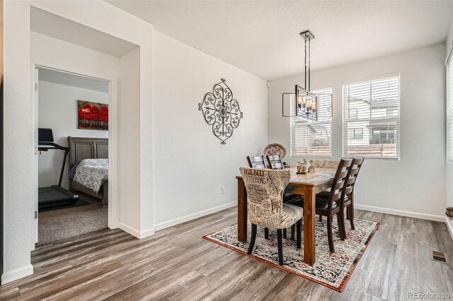 dining area with a chandelier, wood finished floors, and baseboards