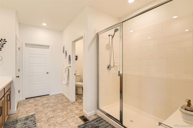 bathroom with a stall shower, vanity, toilet, recessed lighting, and baseboards
