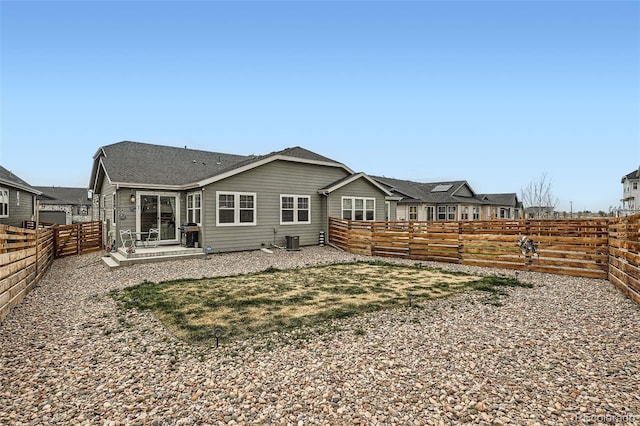 rear view of property with a fenced backyard and central AC unit