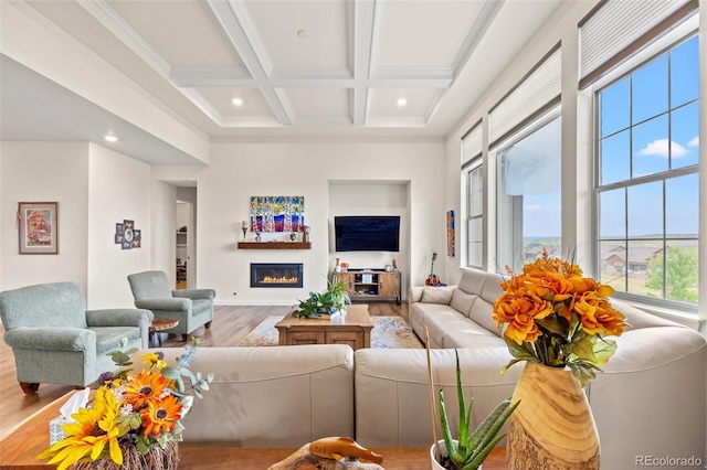 living room with coffered ceiling, crown molding, light wood-type flooring, beamed ceiling, and a high ceiling