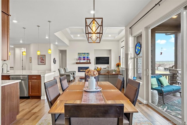 dining area featuring coffered ceiling, sink, light hardwood / wood-style flooring, and a notable chandelier