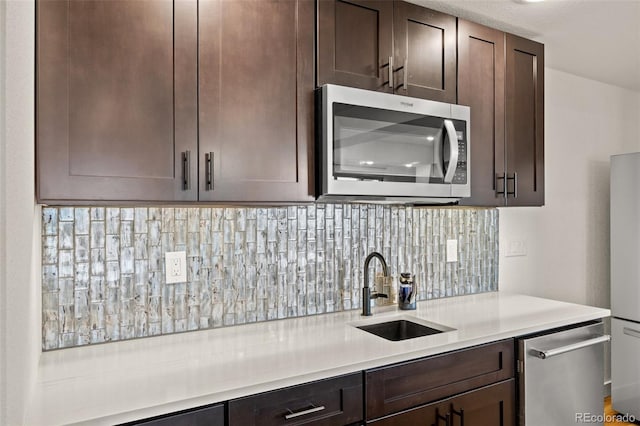 kitchen with stainless steel appliances, sink, and dark brown cabinets