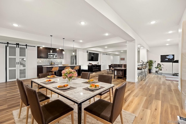 dining area featuring a barn door and light hardwood / wood-style flooring