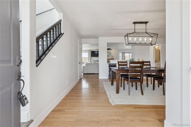 dining space with light wood finished floors, baseboards, and wine cooler