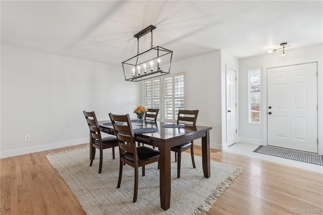 dining room with light wood-type flooring, baseboards, and a notable chandelier