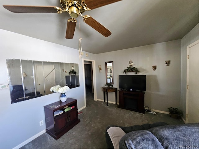 living area with a ceiling fan, vaulted ceiling, dark carpet, and baseboards