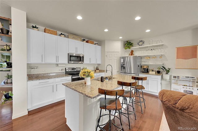 675 W 171st Pl, Broomfield, CO 80023 - kitchen with appliances with stainless steel finishes, a breakfast bar, white cabinets, wood finished floors, and recessed lighting