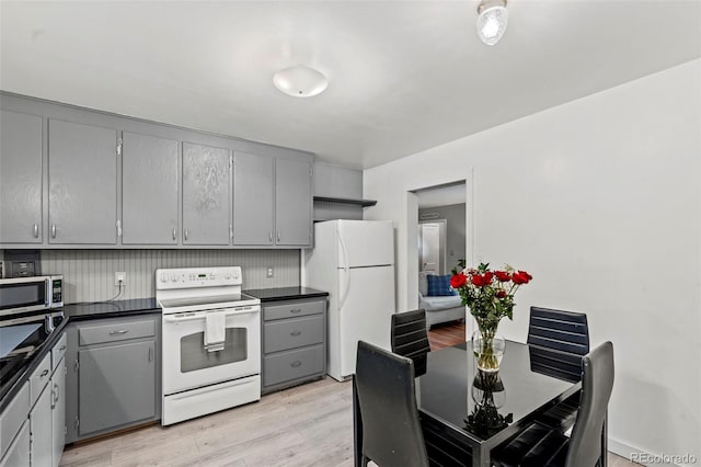 2415 N Logan Ave, Colorado Springs, CO 80907 - kitchen with gray cabinetry, white appliances, dark countertops, and light wood-type flooring