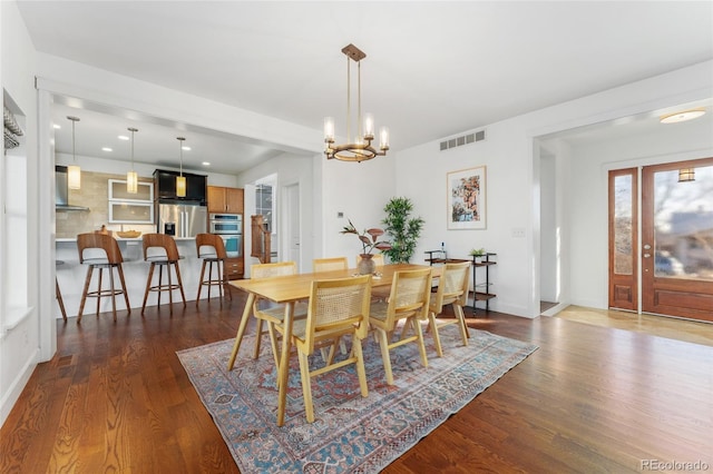 dining space featuring dark wood-type flooring and a notable chandelier