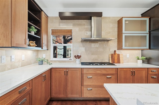 kitchen with tasteful backsplash, light stone countertops, stainless steel gas cooktop, and wall chimney exhaust hood