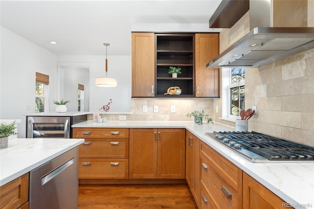 kitchen featuring light stone counters, stainless steel appliances, ventilation hood, and pendant lighting