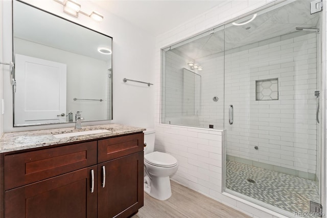 bathroom with vanity, hardwood / wood-style floors, a shower with shower door, and toilet