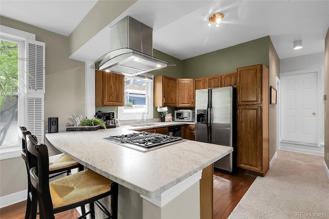 503 15th St, Golden, CO 80401 - kitchen featuring stainless steel appliances, a sink, a peninsula, wall chimney exhaust hood, and brown cabinetry