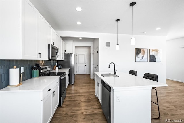 kitchen with a center island with sink, a breakfast bar area, stainless steel appliances, sink, and decorative light fixtures