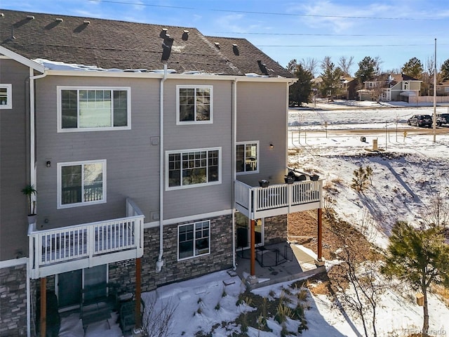 snow covered rear of property featuring a balcony