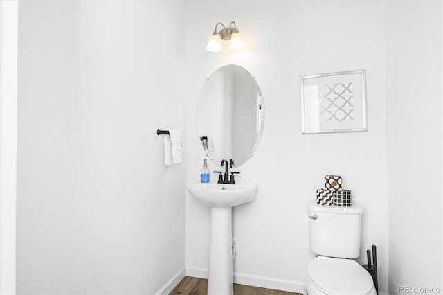 bathroom with toilet, wood-type flooring, and sink