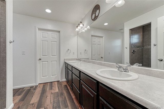 bathroom featuring double vanity, wood finished floors, a sink, and baseboards