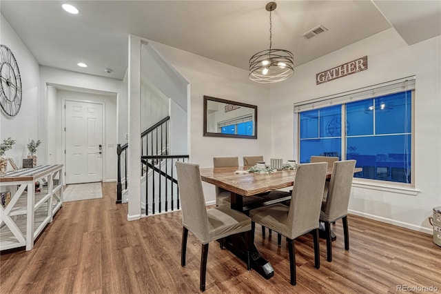 dining room featuring baseboards, stairs, visible vents, and wood finished floors