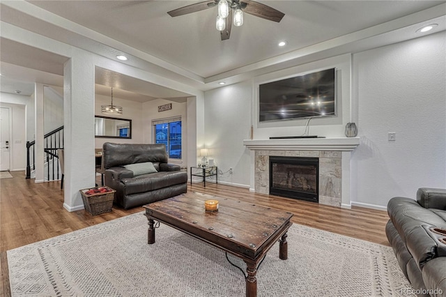 living room with recessed lighting, a tiled fireplace, wood finished floors, baseboards, and stairs