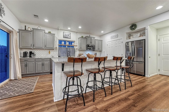 kitchen with appliances with stainless steel finishes, wood finished floors, visible vents, and gray cabinetry