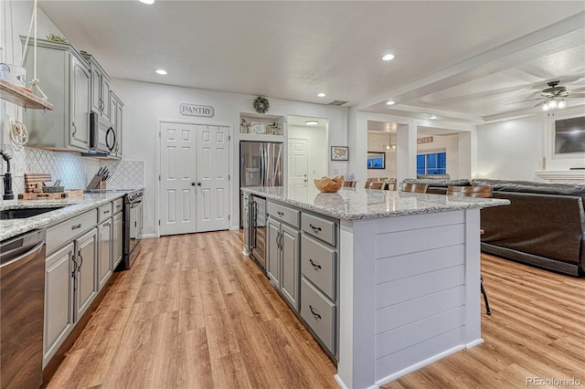 kitchen with stainless steel appliances, a center island, gray cabinets, and open floor plan