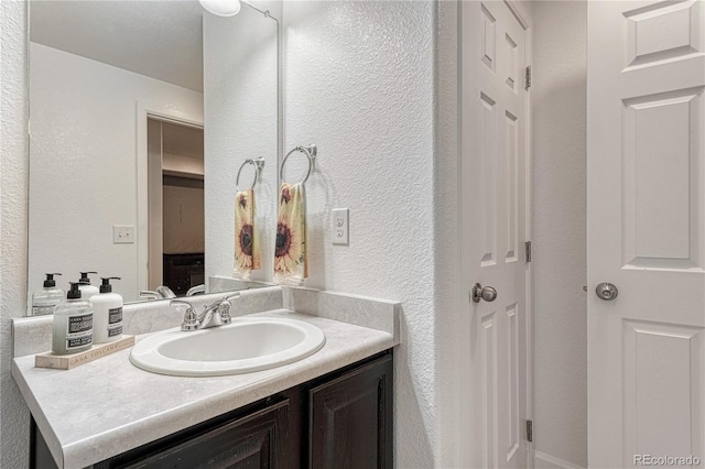 bathroom with a textured wall and vanity