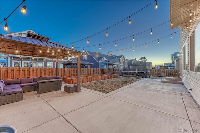 view of patio featuring a trampoline, a fenced backyard, an outdoor living space, and a gazebo