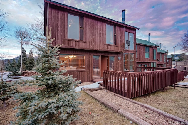 back house at dusk featuring a wooden deck