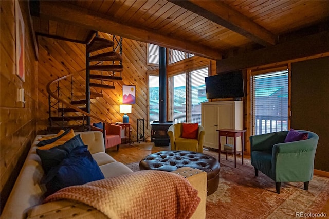 living room featuring beam ceiling, a wood stove, wooden walls, and wooden ceiling