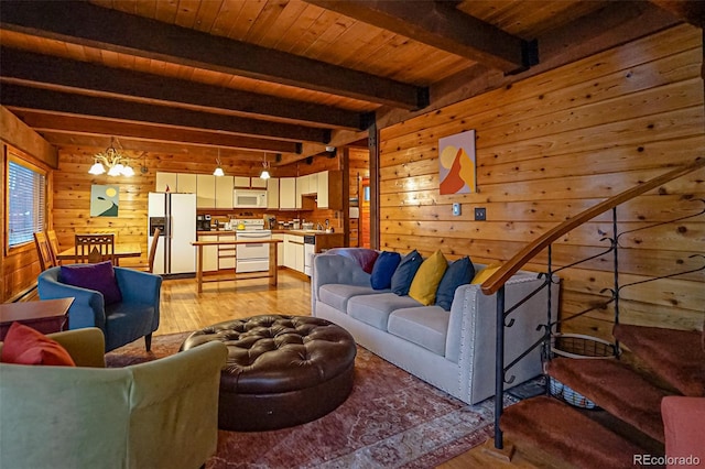 living room featuring wood walls, light hardwood / wood-style flooring, beamed ceiling, and a chandelier